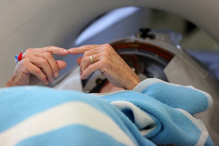 A patient touching fingers together inside the MRI scanner