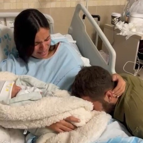 New parents embracing their newborn at the hospital bedside
